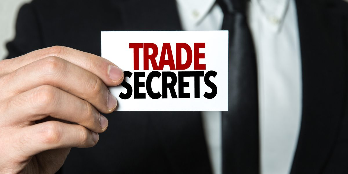Business man holding a sign that says "Trade Secrets" for a case involving trade secret protection - Finkel Law Group