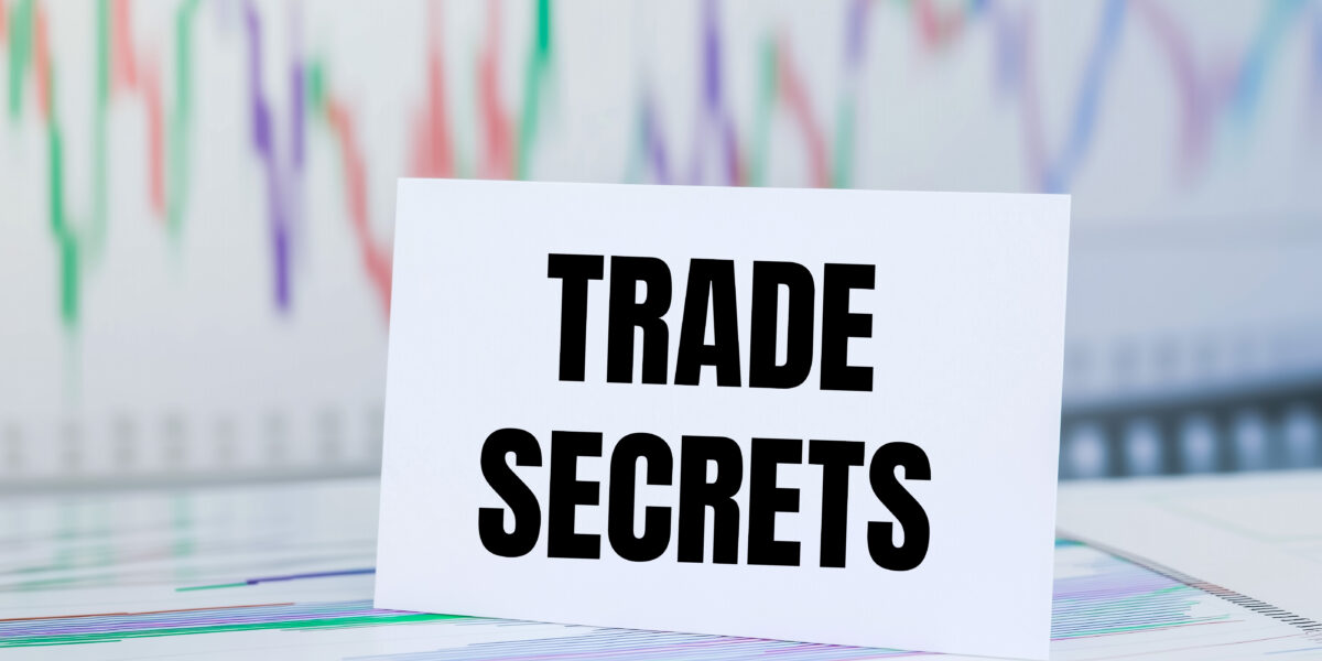 Trade secrets message written on white paper card with financial charts and documents Conceptual trade secrets symbol